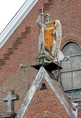 The disintegrating statute of St. Michael stands over the front door of St. Michael Church in Elizabeth Borough -- Lake Fong/Post-Gazette